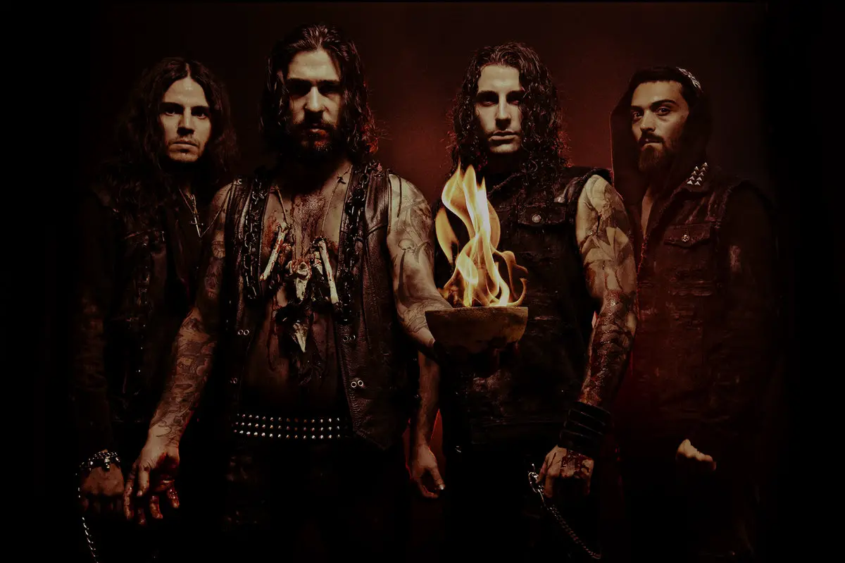 Banda Lucifer's Child posando no lançamento do álbum 'The Wiccan', com membros em frente a um fundo temático de ocultismo e heavy metal.
